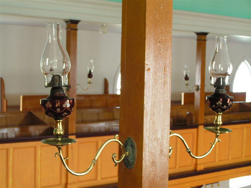 Two single brass lamp branches located in St. Peter's Anglican church, Twillingate, Newfoundland, Canada. These brass lamp branches were donated to the church by John Slade in 1845. 